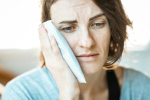 Woman with tooth pain holding an ice pack, representing dental discomfort and fear, treated at Perfect Smile Turkey, an Antalya dental clinic.